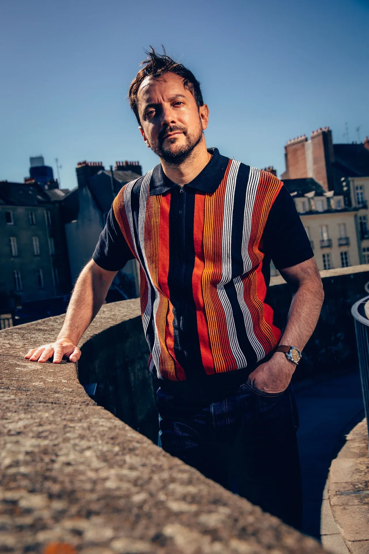Victor Mallet en polo rayé orange appuyé sur un rempart du Château des Ducs