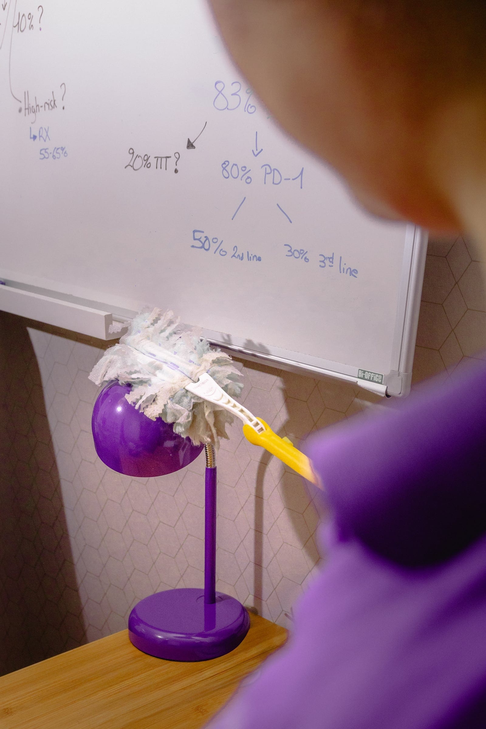Plumeau passé sur une lampe de bureau violette, l'agent flou au premier plan